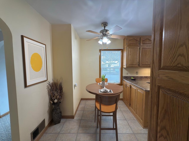 625 10th St, Montevideo, MN 56265 - kitchen featuring dark countertops, light tile patterned floors, ceiling fan, arched walkways, and visible vents