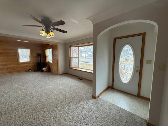 625 10th St, Montevideo, MN 56265 - entrance foyer with wooden walls, a wood stove, light colored carpet, baseboards, and ornamental molding