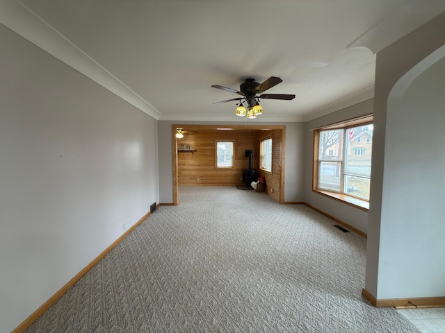 625 10th St, Montevideo, MN 56265 - unfurnished living room with baseboards, carpet, crown molding, wooden walls, and a wood stove