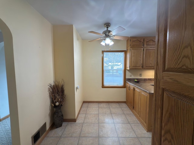 625 10th St, Montevideo, MN 56265 - kitchen featuring dark countertops, light tile patterned floors, ceiling fan, arched walkways, and visible vents