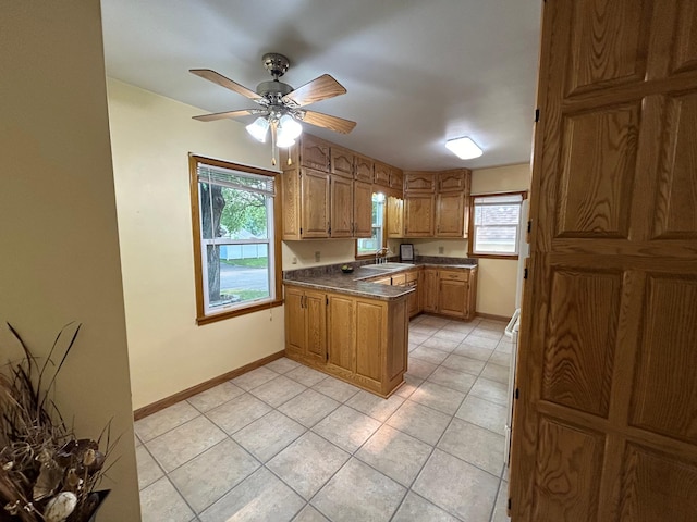 625 10th St, Montevideo, MN 56265 - kitchen featuring a peninsula, dark countertops, a ceiling fan, brown cabinetry, and light tile patterned floors