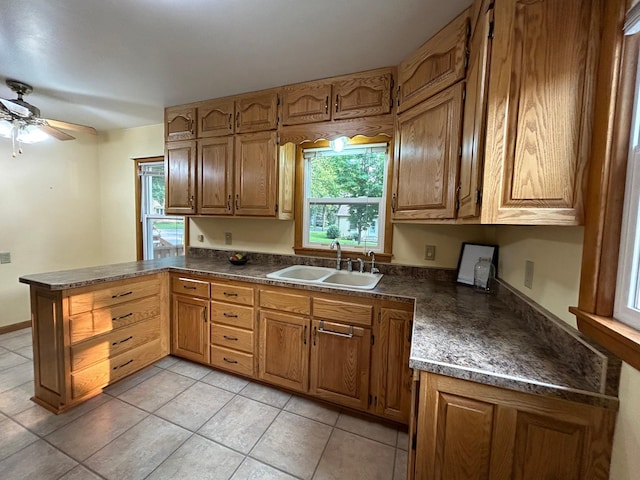 625 10th St, Montevideo, MN 56265 - kitchen with a peninsula, a sink, dark countertops, a ceiling fan, and brown cabinets