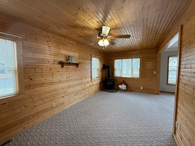 625 10th St, Montevideo, MN 56265 - spare room featuring ceiling fan, a wood stove, carpet, wooden ceiling, and wood walls