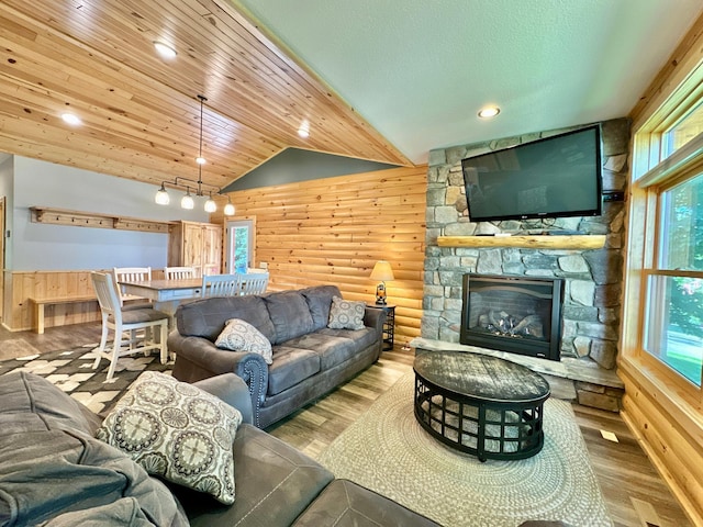 living room with wood walls, a fireplace, lofted ceiling, and light wood-type flooring