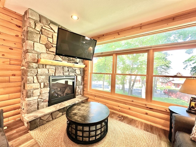 living room with a fireplace, light hardwood / wood-style flooring, log walls, and a textured ceiling