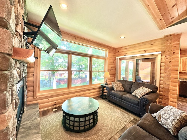 living room with hardwood / wood-style flooring, a fireplace, log walls, and a textured ceiling