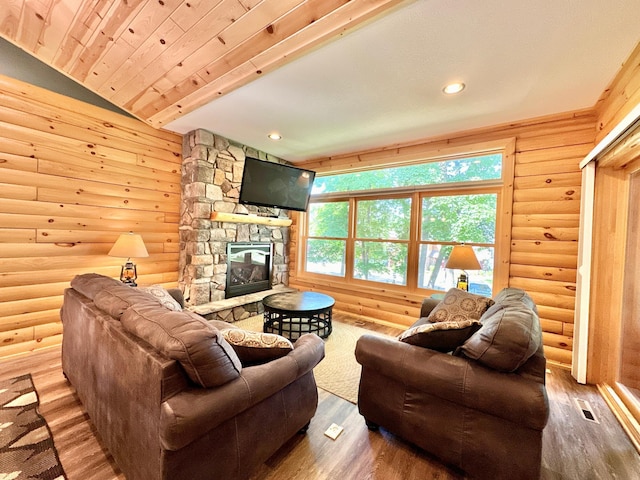 living room with rustic walls, a stone fireplace, wood-type flooring, and lofted ceiling