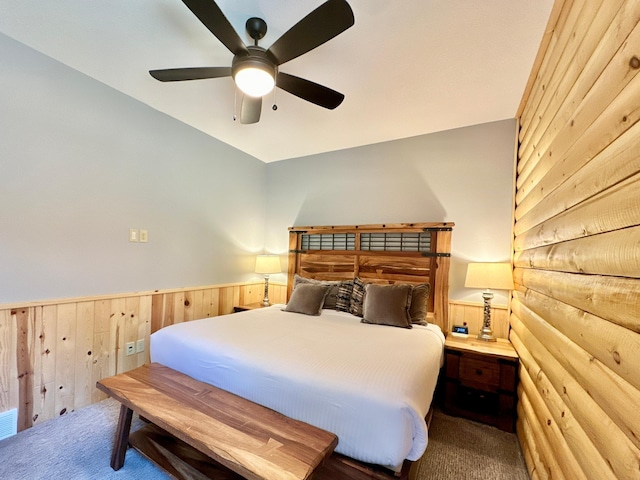 carpeted bedroom with wooden walls and ceiling fan