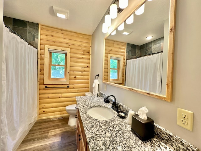 bathroom featuring log walls, wood-type flooring, vanity, and toilet