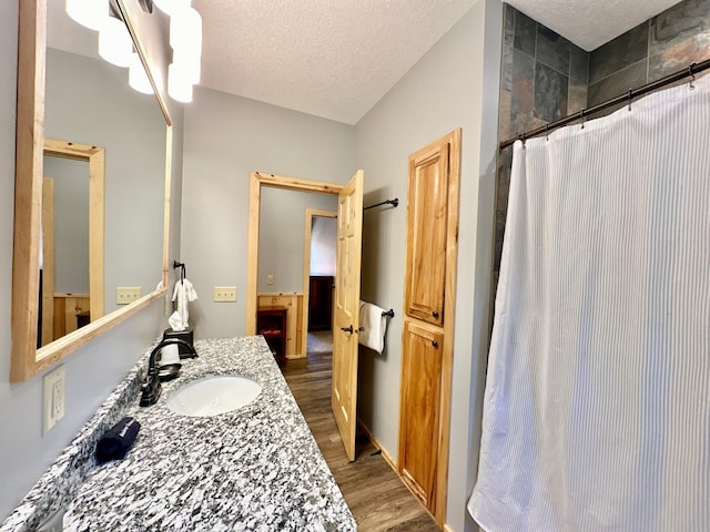 bathroom with hardwood / wood-style floors, a shower with curtain, a textured ceiling, and vanity