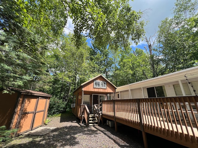 rear view of house with a wooden deck and a storage unit