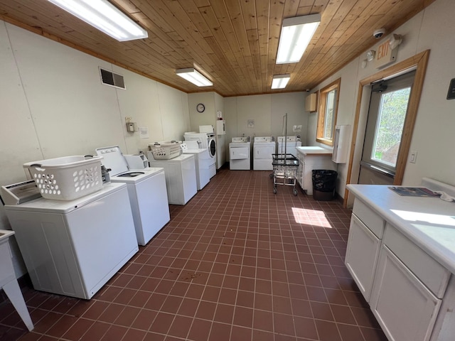 shared laundry area featuring washing machine and clothes dryer, visible vents, wooden ceiling, and dark tile patterned floors