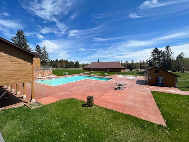 community pool featuring fence, an outdoor structure, a patio, and a yard