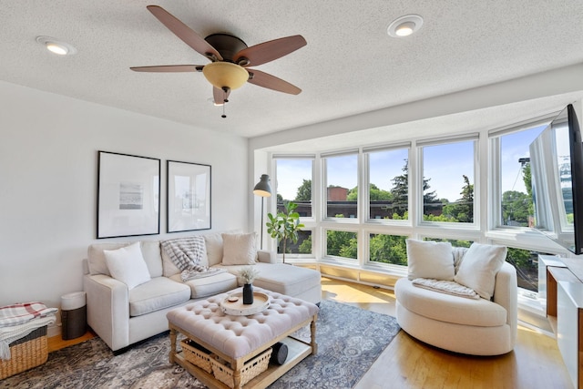 living area featuring a textured ceiling, ceiling fan, and wood finished floors