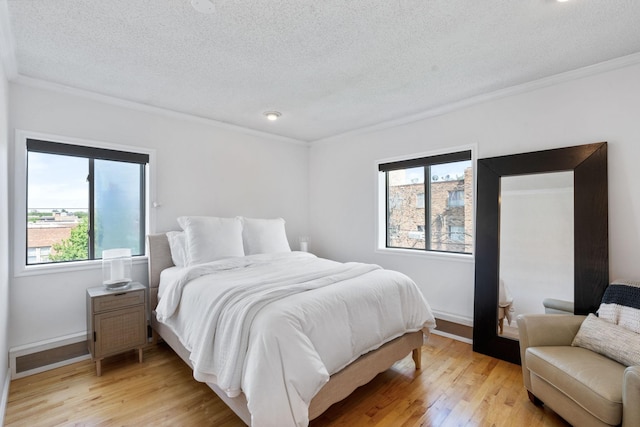 bedroom with a textured ceiling, ornamental molding, baseboards, and light wood-style floors