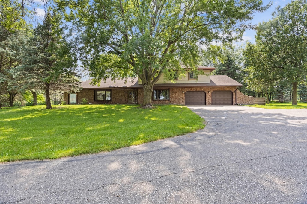 view of front of home with an attached garage, aphalt driveway, a front lawn, and brick siding