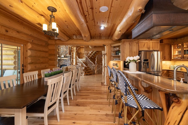 dining room with light hardwood / wood-style flooring, log walls, beam ceiling, wooden ceiling, and sink