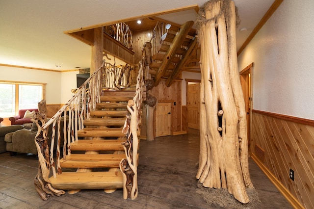 staircase with wooden walls, ornamental molding, and hardwood / wood-style flooring