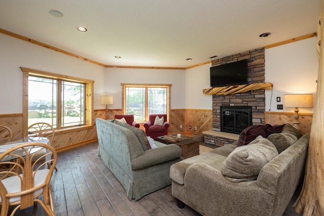 living room featuring hardwood / wood-style flooring, ornamental molding, a healthy amount of sunlight, and a stone fireplace