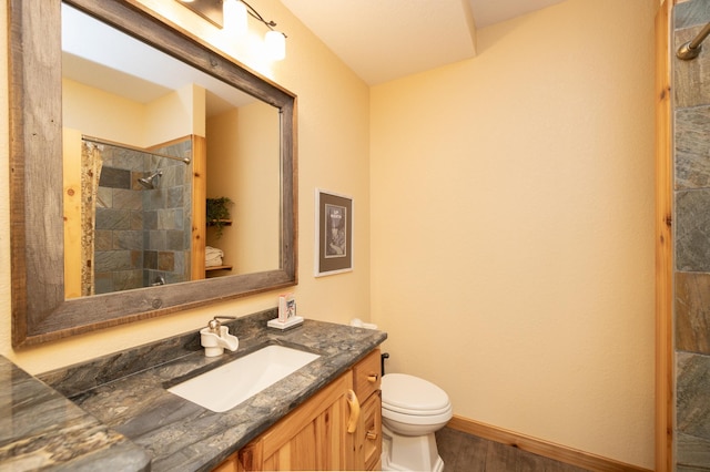 bathroom featuring toilet, hardwood / wood-style floors, tiled shower, and vanity