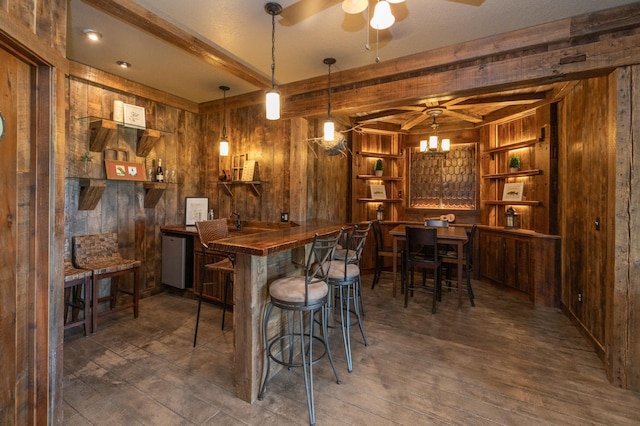 bar with wooden walls, dark wood-type flooring, built in features, pendant lighting, and beam ceiling