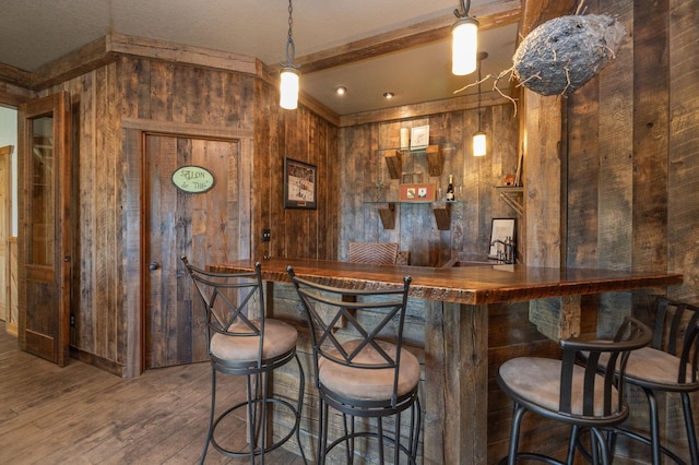 bar with decorative light fixtures, wooden walls, beamed ceiling, wooden counters, and dark wood-type flooring