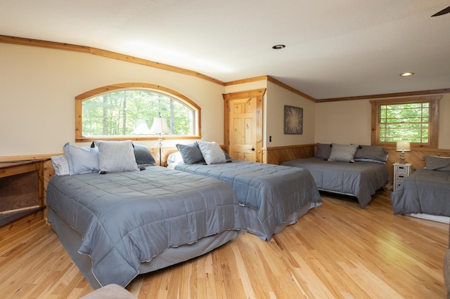 bedroom featuring light hardwood / wood-style floors, multiple windows, and wood walls