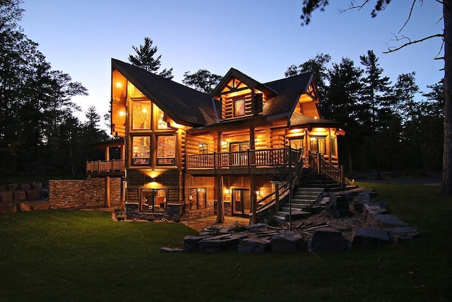 back house at dusk featuring a yard, a deck, and a sunroom