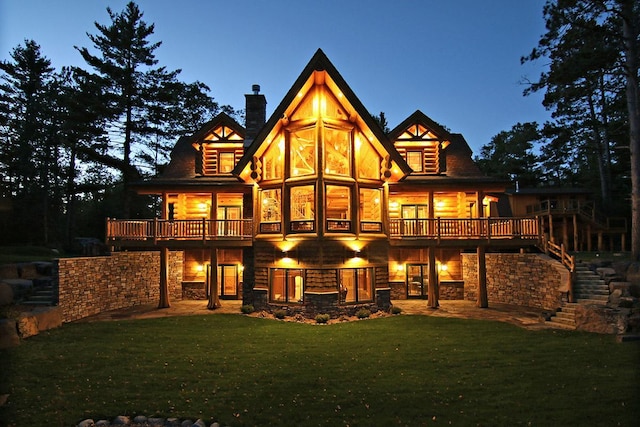 back house at dusk featuring a lawn and a wooden deck