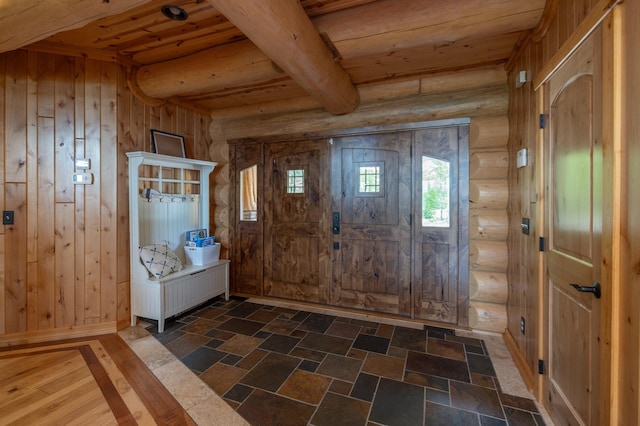 entrance foyer featuring rustic walls, wood ceiling, wooden walls, and beamed ceiling