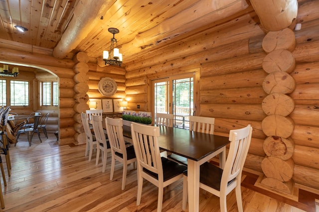 dining area with rustic walls, light hardwood / wood-style flooring, a chandelier, wood ceiling, and beam ceiling