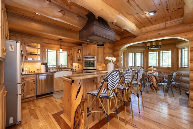 kitchen with wooden ceiling, appliances with stainless steel finishes, log walls, sink, and light hardwood / wood-style flooring