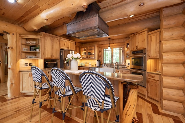 kitchen featuring decorative light fixtures, log walls, light wood-type flooring, and appliances with stainless steel finishes