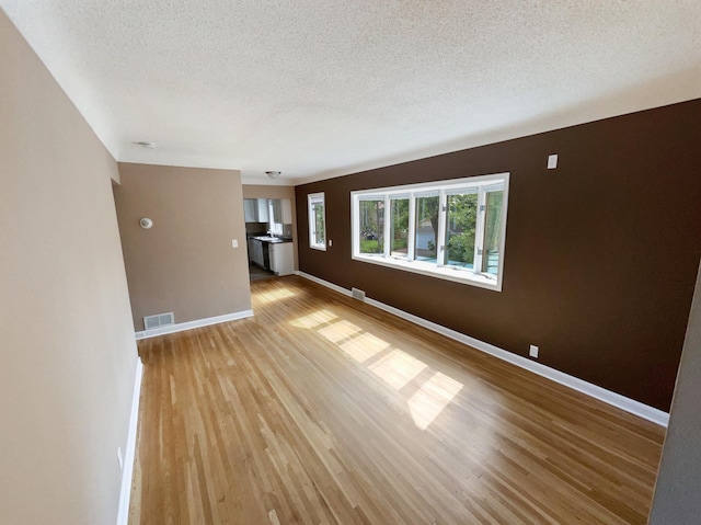 unfurnished room featuring light hardwood / wood-style floors and a textured ceiling