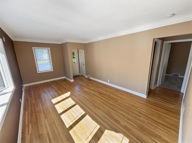 empty room featuring a textured ceiling, vaulted ceiling, and light hardwood / wood-style flooring