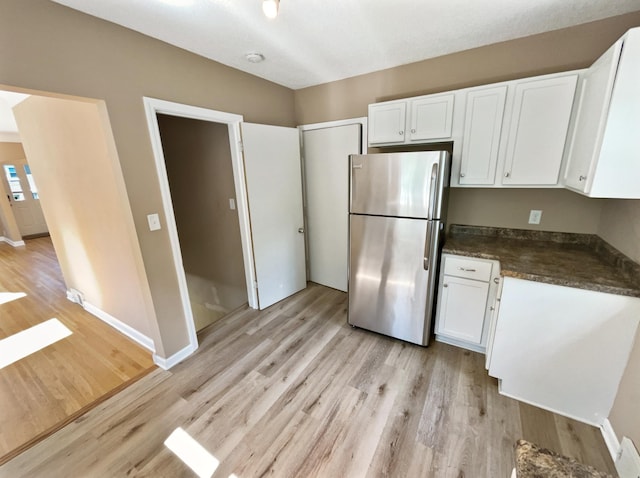 kitchen featuring white cabinets, stainless steel refrigerator, and light hardwood / wood-style floors