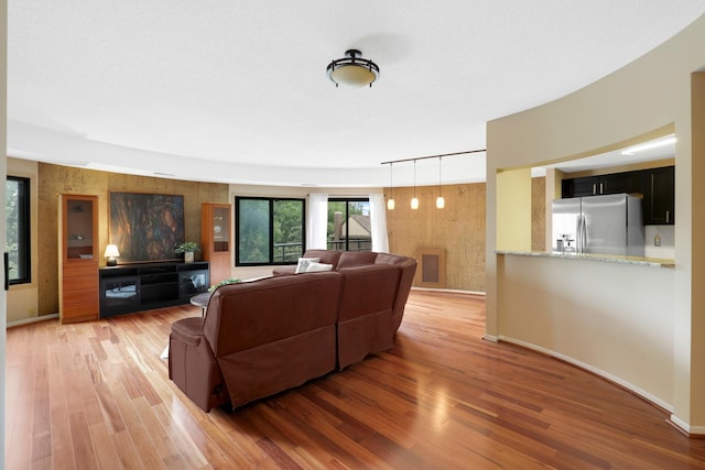 living room with light hardwood / wood-style floors and wood walls