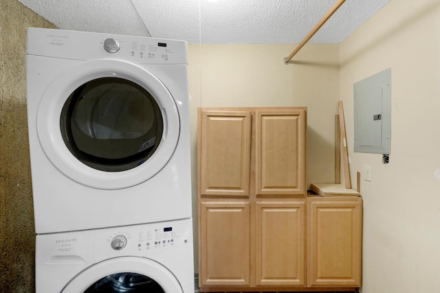 clothes washing area with cabinets, a textured ceiling, electric panel, and stacked washer and clothes dryer