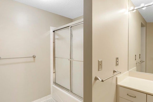 bathroom with a textured ceiling, shower / bath combination with glass door, tile patterned floors, and vanity