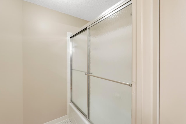 bathroom featuring tile patterned floors, a textured ceiling, and shower / bath combination with glass door