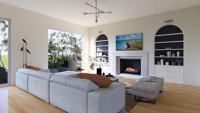 living room with built in shelves, light wood-type flooring, and an inviting chandelier