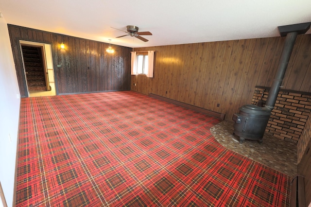 unfurnished room with ceiling fan and a wood stove