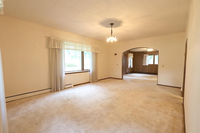 carpeted empty room featuring a baseboard radiator and a chandelier