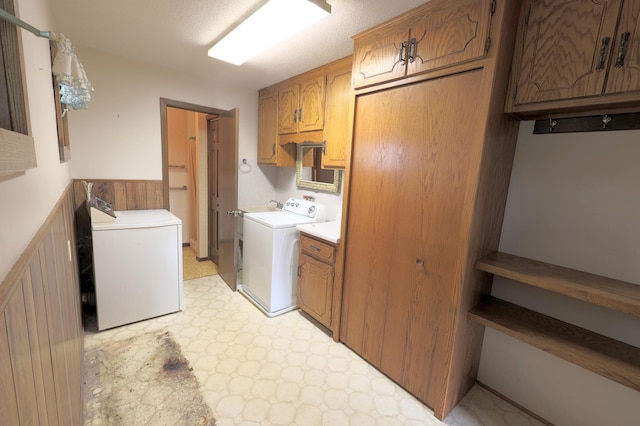 clothes washing area featuring light tile patterned flooring, washing machine and clothes dryer, and cabinets