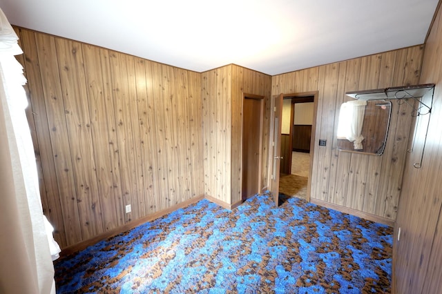 unfurnished bedroom with carpet and wood walls