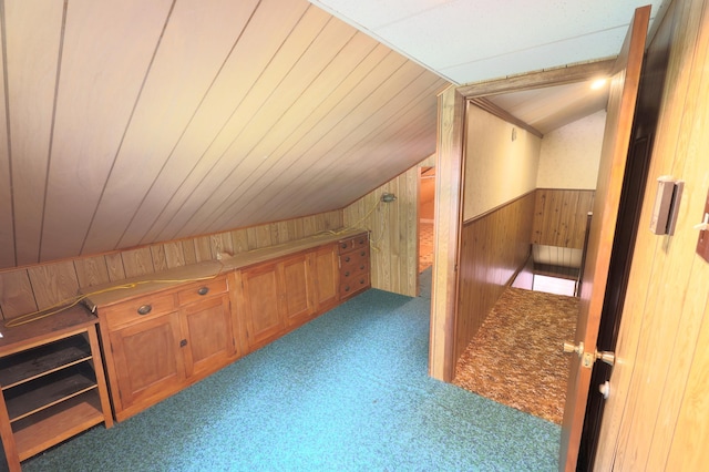 additional living space featuring wooden walls, lofted ceiling, and carpet