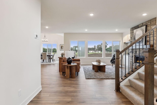 living room with a chandelier, a fireplace, and wood-type flooring