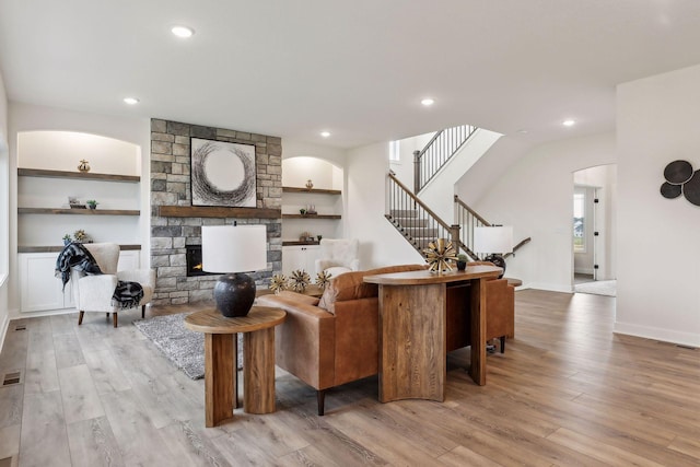 living room featuring a fireplace, built in features, and light hardwood / wood-style floors