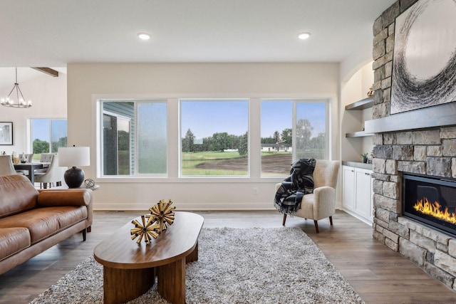 living room featuring a wealth of natural light, an inviting chandelier, a fireplace, and hardwood / wood-style floors