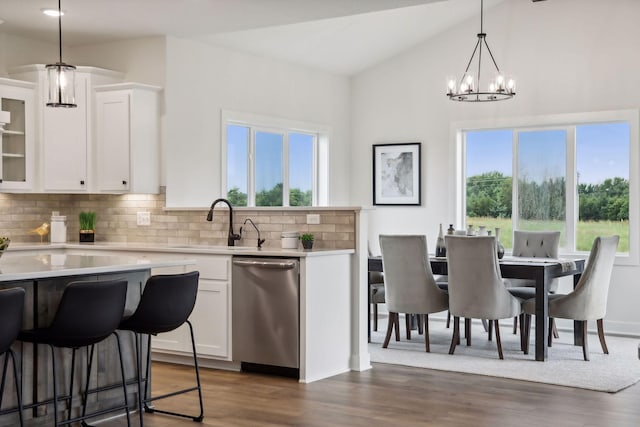 kitchen with dishwasher, hanging light fixtures, white cabinets, a notable chandelier, and decorative backsplash